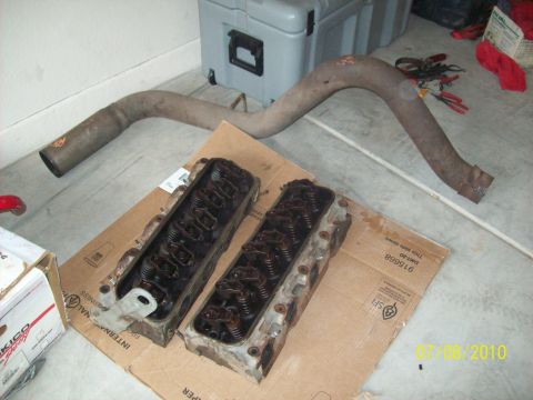 1985 Ford Bronco - Engine cylinder heads and exhaust pipe are laid out on cardboard, with a toolbox and other items in the background. The photo is dated 07/0…