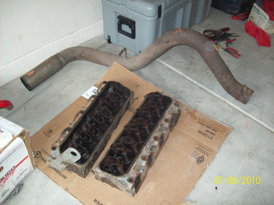 Engine cylinder heads and exhaust pipe on cardboard