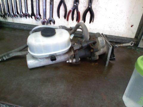 1990 Ford Bronco - A brake master cylinder assembly is shown, detached from a vehicle, on a workshop bench.
