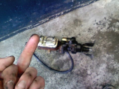 1990 Ford Bronco - A brake master cylinder is shown, with a dirty finger obscuring part of the view.