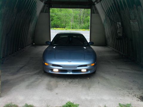 1994 Ford Probe - A blue 1994 Ford Probe is parked head-on inside a metal Quonset hut garage.