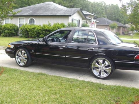 1995 Mercury Grand Marquis - Black 1995 Mercury Grand Marquis with custom chrome wheels sits on a suburban driveway.