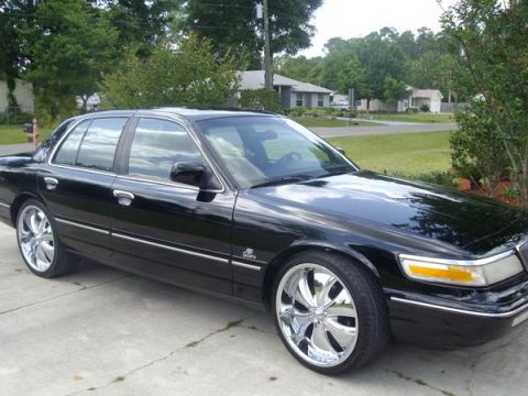 1995 Mercury Grand Marquis - A black 1995 Mercury Grand Marquis is shown from a three-quarter front view, custom chrome wheels.