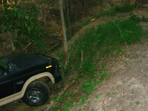 1983 Ford Bronco - This SUV is navigating a steep, wooded trail with loose dirt and vegetation.