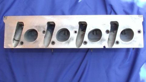 1973 Ford Mustang - An engine cylinder head is shown from the intake port side against a blue background.