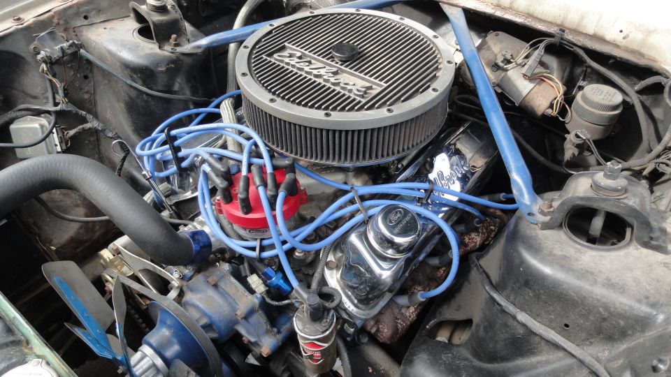 Small-block V8 with Edelbrock air cleaner, blue plug wires and chrome Ford valve covers