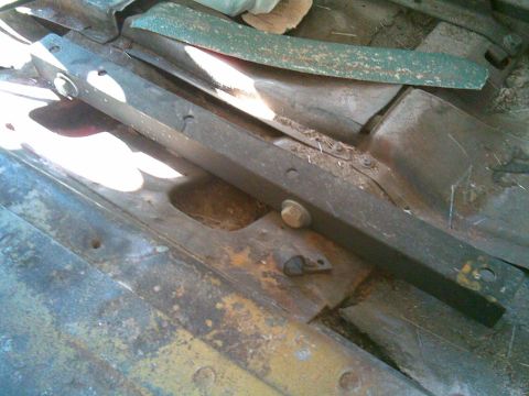 1972 Ford Ranchero - Close-up underbody view of a rusty leaf spring stack and frame rail with bolts and hangers on a vehicle.
