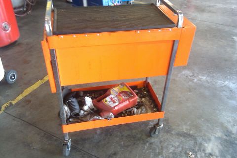 2000 Mercury Grand Marquis - An orange tool cart is shown with a red oil bottle and other items stored in its lower compartment.