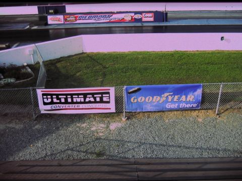1992 Ford Mustang - A drag strip scene with advertising banners visible on a chain-link fence.