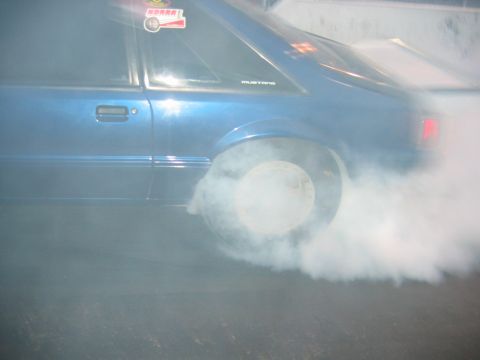 1992 Ford Mustang - A blue 1992 Ford Mustang performs a burnout, kicking up a large cloud of smoke.