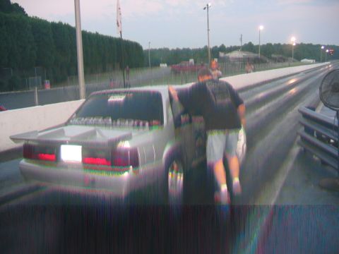 1992 Ford Mustang - A person leans on a 1992 Ford Mustang at a drag strip, ready for a race.