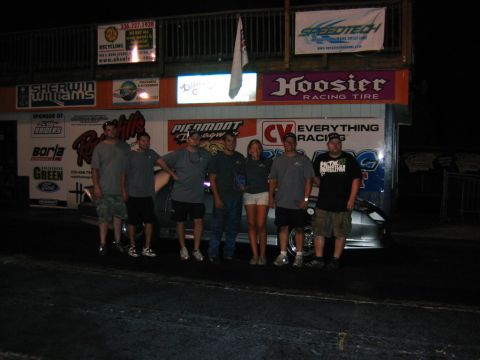 1992 Ford Mustang - People gathered at a race track with various sponsor banners visible in the background.