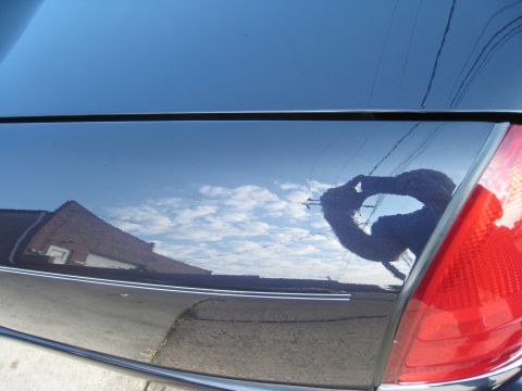 1999 Ford Crown Victoria - Reflection on the side panel of a dark blue car shows a brick building and the photographer.