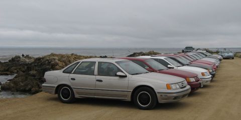 2003 Ford Taurus - A first-generation Ford Taurus SHO in champagne/silver with body-color side skirts and black basketweave-style wheels leads a long row of T…
