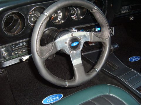 1973 Ford Ranchero - The interior of a 1973 Ford Ranchero features an aftermarket steering wheel and original Ford badging on the floor mats.