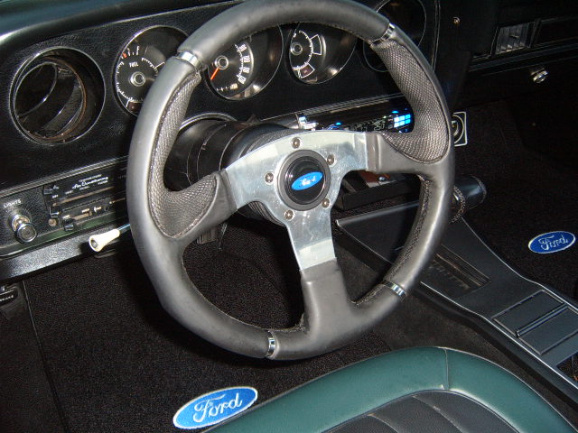 Interior shot of a 1973 Ford Ranchero showing the steering wheel, dashboard, and floor mats with Ford logos