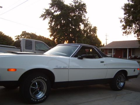 1973 Ford Ranchero - A white 1973 Ford Ranchero is parked in front of a house, with a pickup truck visible behind it.