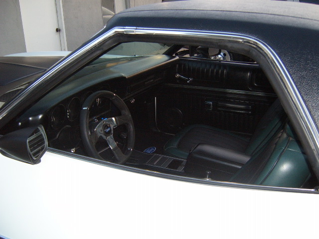 White 1973 Ford Ranchero interior with black dashboard, green seats, and aftermarket steering wheel