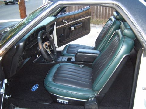 1973 Ford Ranchero - The interior of a 1973 Ford Ranchero features green and black vinyl seats, a black dashboard, and a Ford logo on the floor mat.