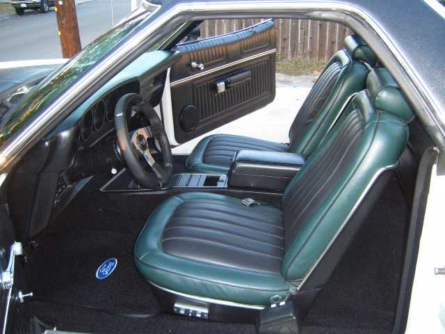 1973 Ford Ranchero interior with green and black seats and a Ford logo on the carpet