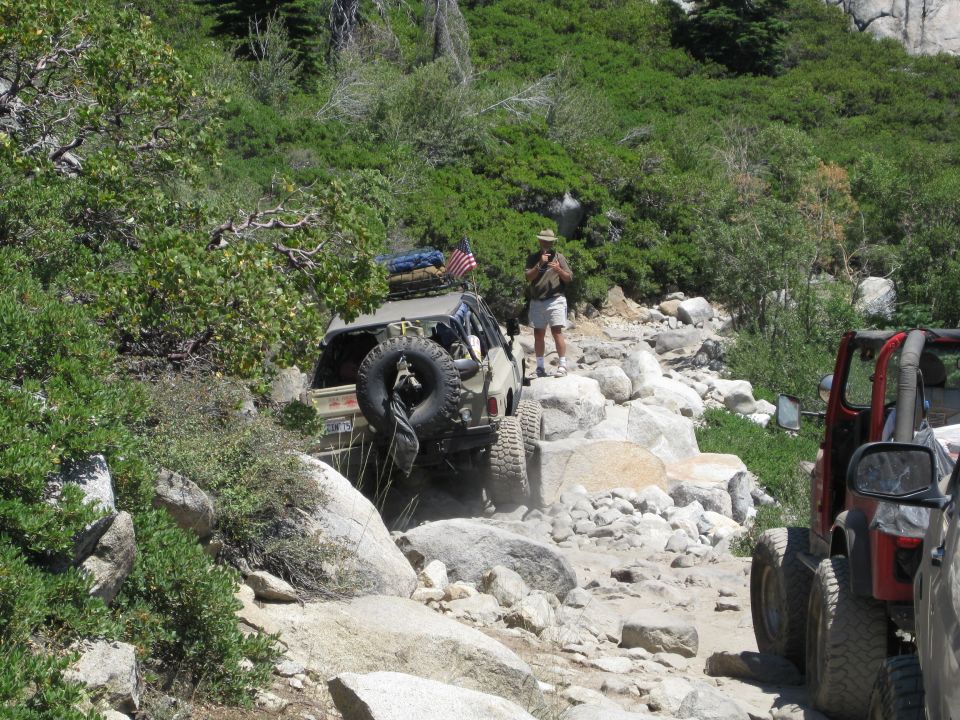 Tan SUV with spare tire on rear, navigating a rocky mountain trail