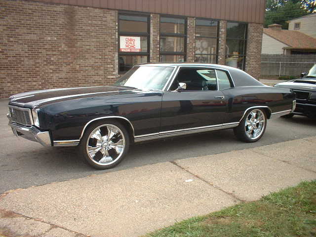 Dark blue 1970s Chevrolet Monte Carlo with chrome wheels parked on a sidewalk