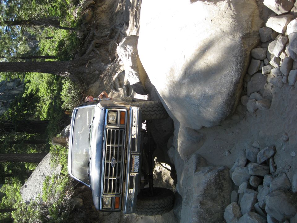 Ford Bronco navigating a rocky trail, front grille visible. License plate reads PCCGH007