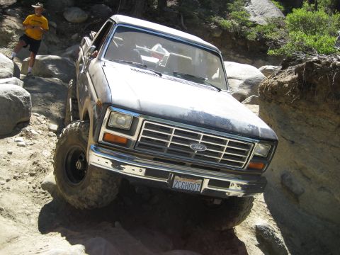 1986 Ford Bronco - This Ford F-Series truck navigates a rocky trail with a person observing the action.