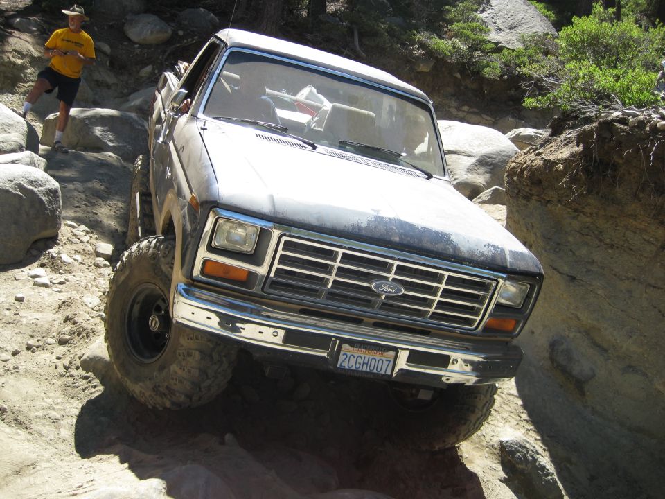 Ford F-Series truck going off-road over rocks. Guy in yellow shirt watching