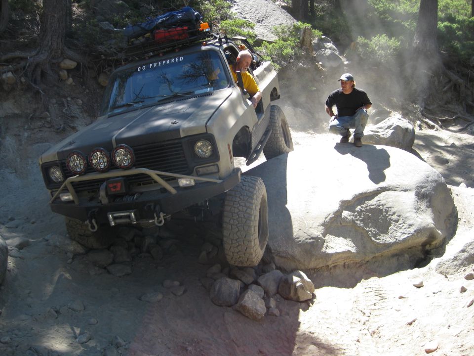 Modified 1973 Chevrolet K5 Blazer off-roading on a dirt trail with large rocks