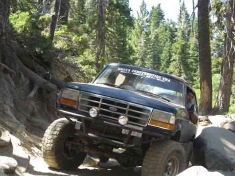 1986 Ford Bronco - This 1992 Ford Bronco is shown off-roading on a rocky trail, with a "Under Construction 4x4" sticker visible on the windshield.