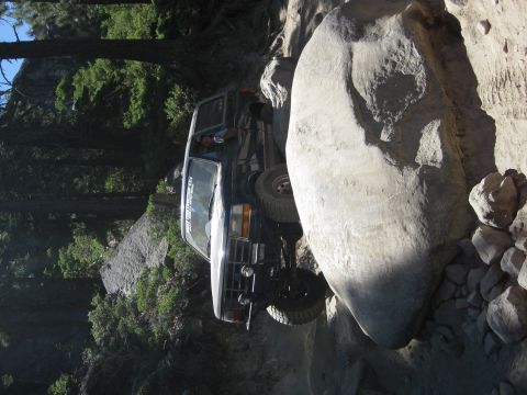 1986 Ford Bronco - This SUV is maneuvering through a challenging off-road obstacle course with large boulders.