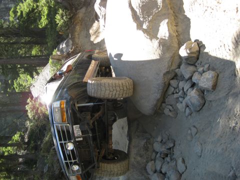 1986 Ford Bronco - This black SUV appears to be stuck on a rocky incline, with its front grille and tires clearly visible.