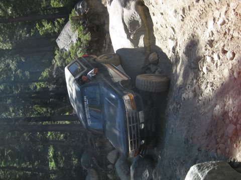 1986 Ford Bronco - A dark blue 1987 Ford Bronco is stuck on a steep, rocky off-road trail.