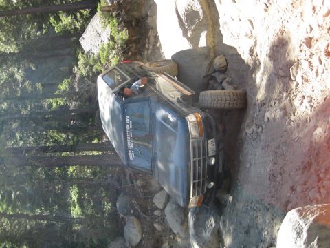 1986 Ford Bronco - This dark blue 1987 Ford Bronco navigates a challenging, rocky off-road path, demonstrating its 4x4 capabilities.