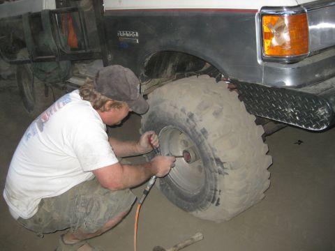 1986 Ford Bronco - A man uses an air tool to inflate the large tire of a 1986 Ford Bronco.