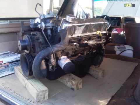 1986 Ford Bronco - Engine assembly, likely a V8, is staged on wooden blocks inside a vehicle's cargo area.