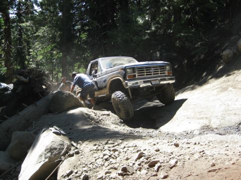 1986 Ford Bronco - A 1986 Ford Bronco tackles a challenging off-road trail with assistance from a spotter.