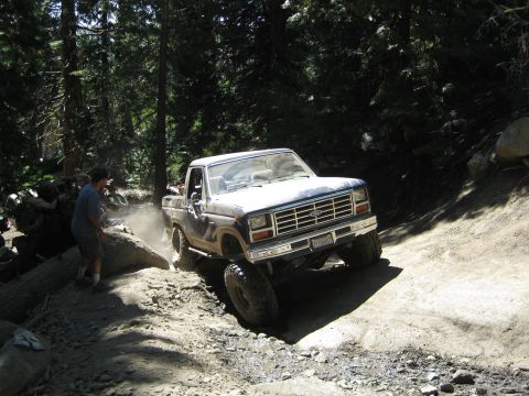 1986 Ford Bronco - Ford pickup truck on a challenging off-road trail in a wooded area.