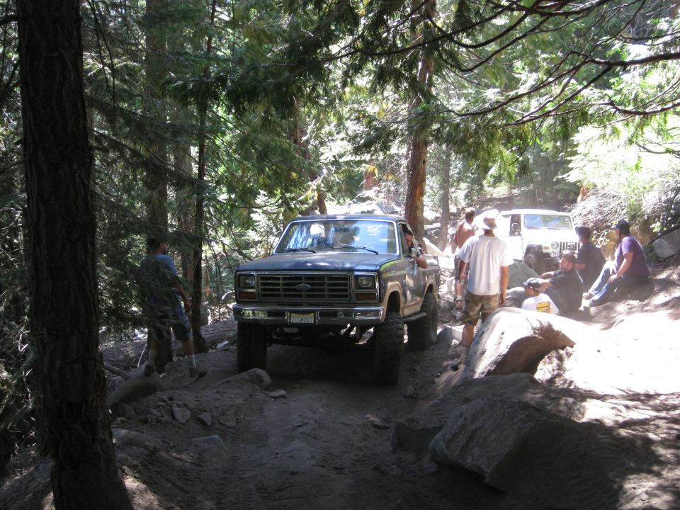 Ford F-Series pickup truck on a rocky trail with people around. Another Jeep is visible behind it