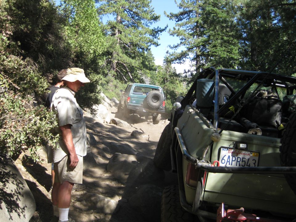 Green 1986 Ford Bronco on rocky trail, rear view