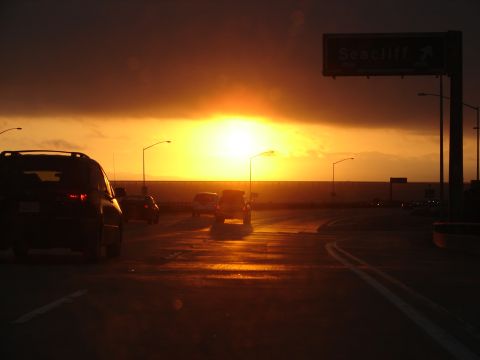 1992 Ford Taurus - Cars drive on a highway towards a dramatic sunset, with a Seacliff sign visible overhead.