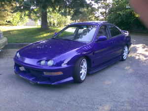 1998 Acura Integra - A purple sedan is parked on a paved surface with trees in the background. A watermark is visible at the bottom right.