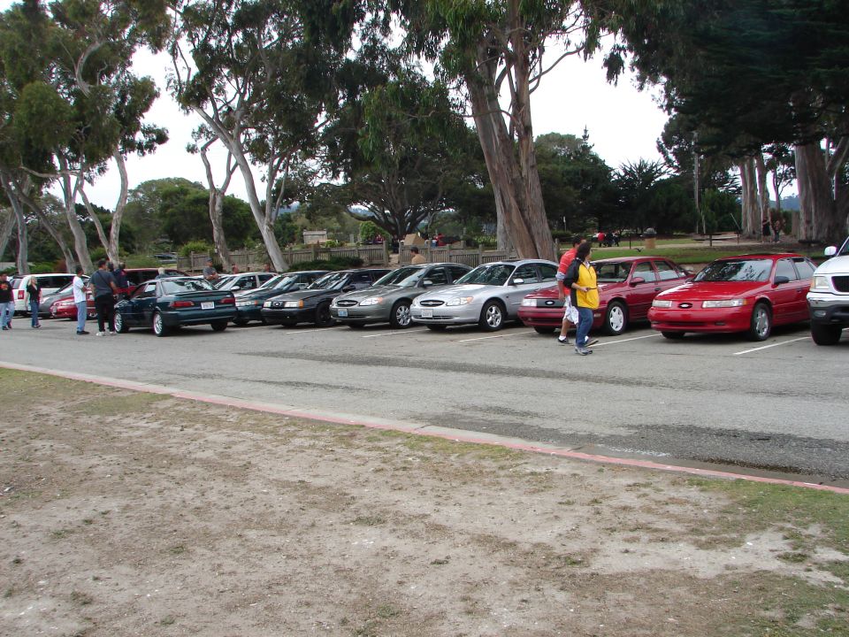 Line of sedans and a wagon parked, one red wagon prominent