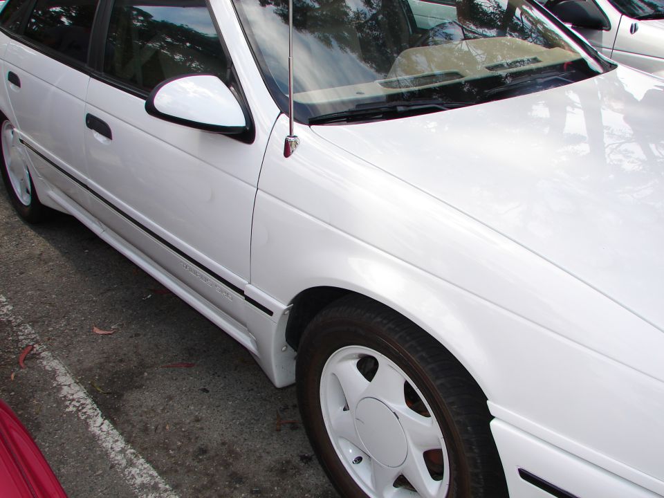 White 1992 Ford Taurus sedan with a black pinstripe and body kit, seen from the front three-quarter angle