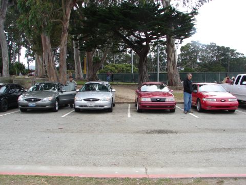 1992 Ford Taurus - Two red Ford Taurus sedans are parked side-by-side, with the one on the right clearly showing its 1992 model year grille.