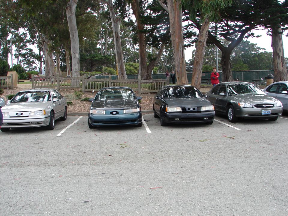 Four Ford Taurus cars parked in a lot, three in the foreground