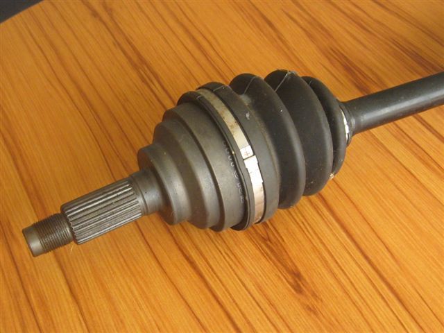 CV axle shaft with splined end and rubber boot on wooden surface