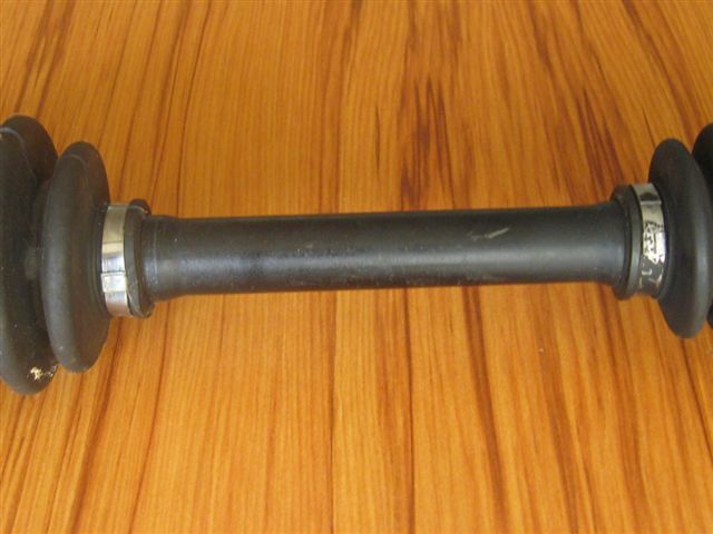 CV axle shaft with rubber boots and metal clamps on a wood-grain surface