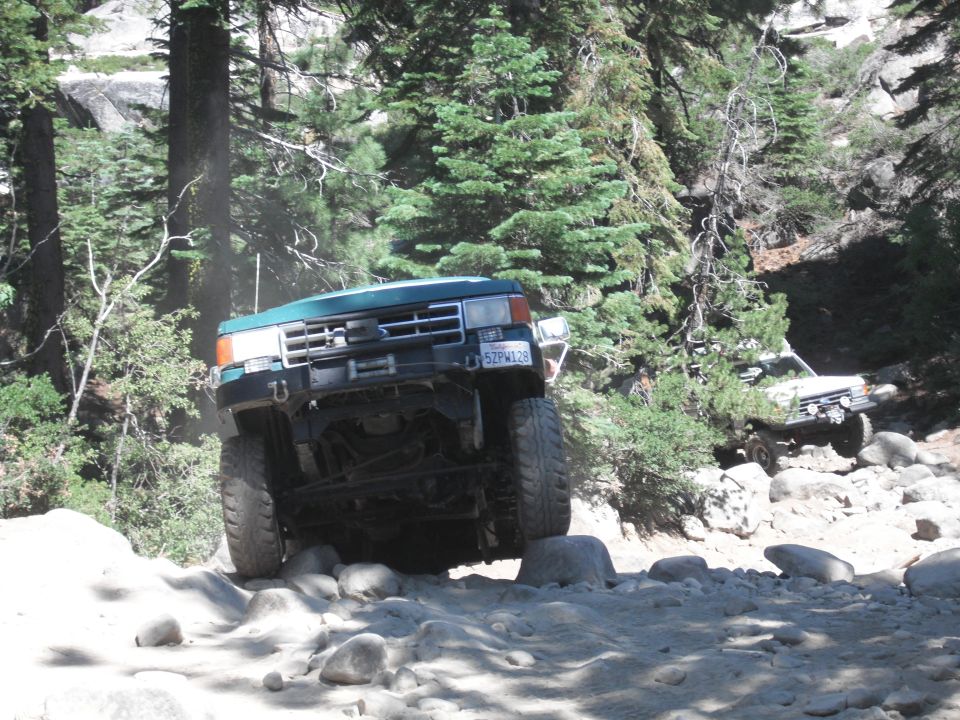 1991 Ford Bronco navigating a rocky off-road trail with another vehicle behind it